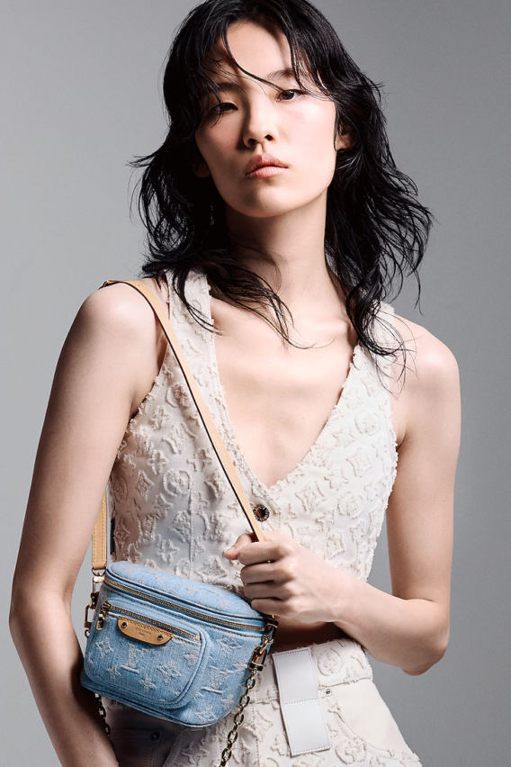 A summery Louis Vuitton Mini Bumbag in vintage-look sky blue Monogram denim, featuring a bleached and stonewashed finish, gold-tone hardware, a front pocket with an embossed leather label, and versatile removable chain and adjustable strap options.